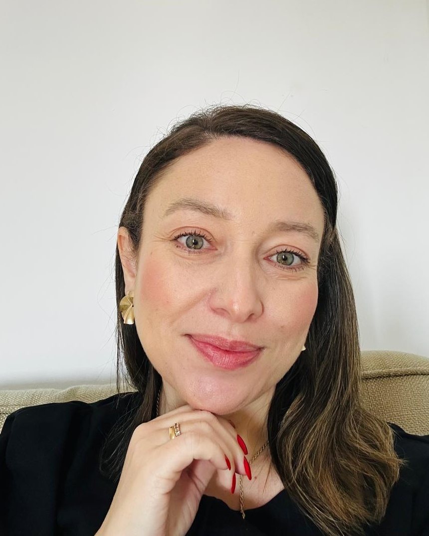 Paola Farias sorrindo, com a mão apoiada no queixo